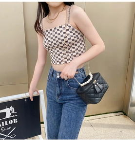 Sac seau noir matelassé avec poignée en perles et chaîne dorée porté par un modèle