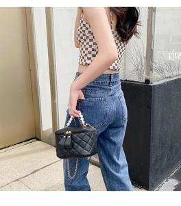 Détail d'un sac seau noir matelassé avec poignée en perles et bandoulière en chaîne
