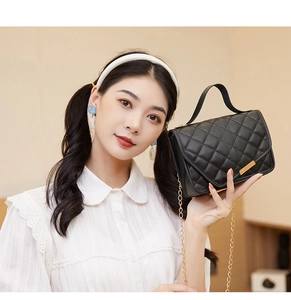 Macro shot of black quilted faux leather handbag with elegant gold metal buckle details