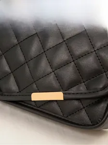 Macro detail of black quilted leather bag featuring premium golden metal hardware accent