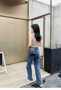 Détail d'un sac seau noir matelassé avec poignée en perles et chaîne sur un mannequin