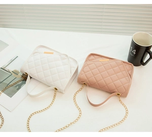 Detail of embroidered crossbody bags in white and pink with quilted pattern and chain straps