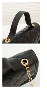 Close-up of black quilted faux leather bag with elegant gold metal chain and handle hardware
