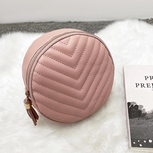 Pale pink round crossbody bag with V-quilted stitching and tassel detail on soft faux fur