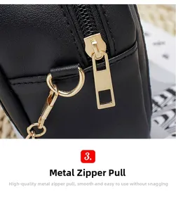 Detail of smooth gold zipper hardware on black textured leather crossbody bag