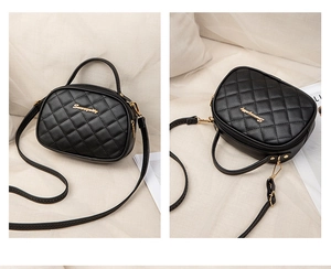 Close-up of black quilted handbag with golden metal logo and shiny synthetic leather