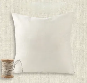 Close-up of white twill fabric pillowcase with natural linen background and wooden spool