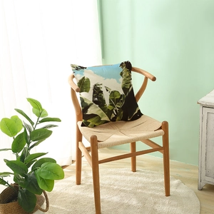 Tropical banana leaf print pillow case on a wooden chair in a bright Nordic home setting