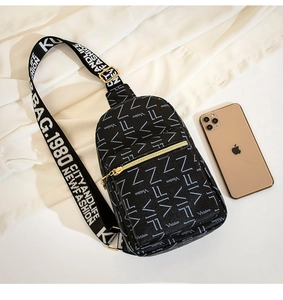 Close-up of a black printed chest bag with gold zipper and graphic logo shoulder strap