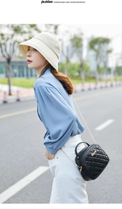 Close-up of quilted black crossbody bag with gold chain strap and brand logo detail