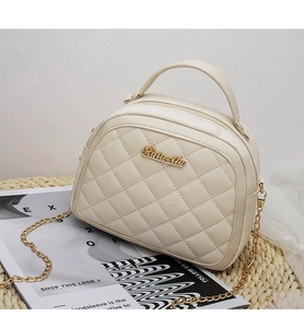 Close-up of beige quilted crossbody bag with gold metal logo and chain strap detail