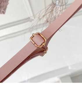 Detail of pink leather shoulder strap with golden metal buckle for crossbody bag