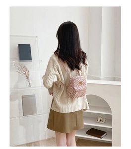 Detail of pink printed mini backpack with front zipper pocket on a model with white sweater