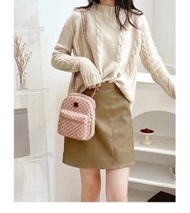 Close-up of a pink checkered mini backpack with metal zipper detail on a fashion model