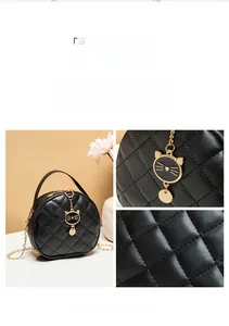 Detailed view of black quilted mini round bag featuring a gold cat charm and chain strap