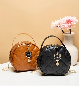 Detail of round quilted mini bags in black and brown with cat-shaped metal charms