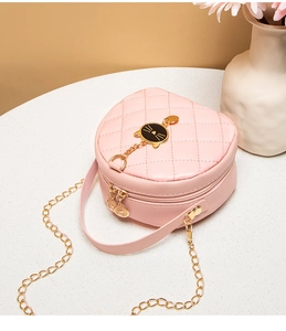 Detailed view of pink quilted round bag with gold cat-head metal ornament and chain strap