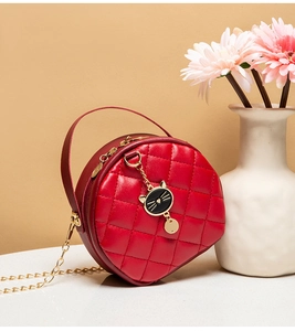Detail of red quilted mini bag with gold chain strap and a cute cat head charm pendant