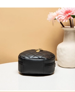 Close-up of quilted black mini round bag with gold hardware on white surface