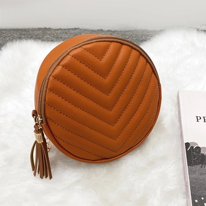 Quilted round crossbody bag in caramel brown faux leather with elegant side tassel detail