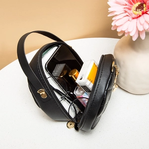Black quilted mini circle bag with gold hardware showing phone and lipstick storage
