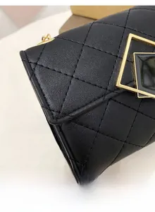 Nahaufnahme der schwarzen Steppleder-Textur und des goldenen Metallverschlusses der Tasche