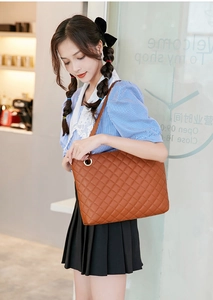 Close-up of brown quilted faux leather tote bag with gold ring handle detailing