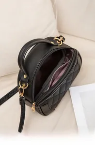 Detail view of the black quilted shoulder bag featuring gold hardware and lilac lining