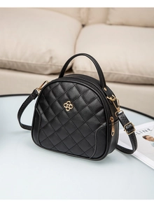 Detail of black quilted leather mini shell bag with golden flower clasp and stitching