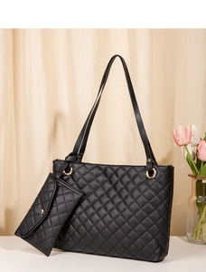 Close-up of black quilted tote bag with gold hardware and a matching small envelope pouch