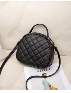 Close-up of black quilted handbag with gold hardware on a beige textured fabric