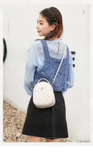 Photo extérieure d'un sac bandoulière blanc matelassé avec fleur dorée sur un mannequin