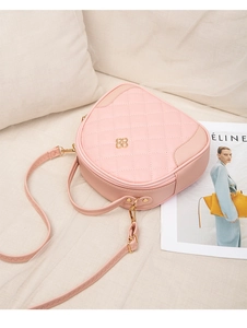 Detail view of pink quilted leather texture and gold flower emblem on a mini crossbody bag