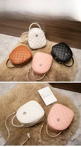 Détail de quatre mini sacs à main matelassés en blanc, rose, marron et noir sur peluche