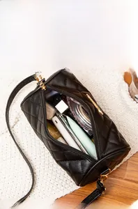 Details der schwarzen gesteppten Zylindertasche mit geräumigem Innenraum und Zubehör