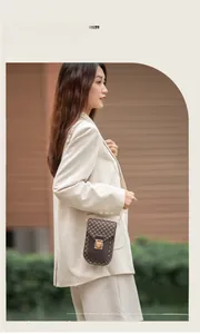 Close-up of vintage brown monogram phone bag with gold clasp and chain strap on model