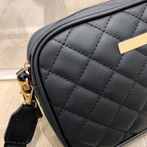 Detail of black quilted shoulder bag with gold hardware and smooth leather texture