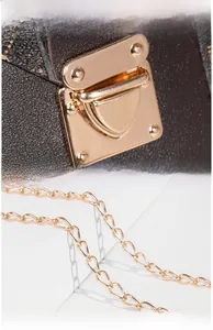 Detailed macro view of the golden vacuum-plated hardware lock and chain on brown leather bag
