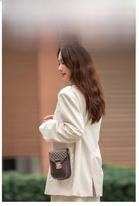 Retro small brown crossbody phone bag with geometric pattern and gold chain on model