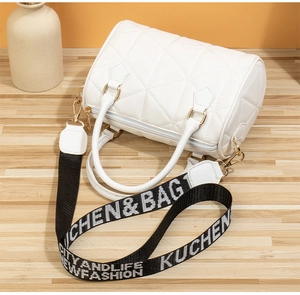 Detailansicht der weißen gesteppten Zylindertasche mit breitem Textilgurt und Goldbeschlägen