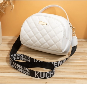 Détail d'un sac bandoulière blanc matelassé avec boucle dorée et large sangle