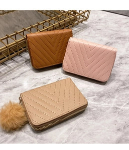 Three V-stitched short wallets in brown, pink, and khaki with a fluffy pompom keychain detail