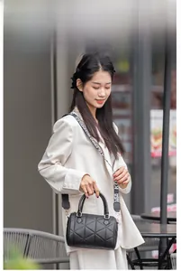 Streetstyle-Aufnahme einer schwarzen Stepptasche mit breitem Gurt an einem Modell