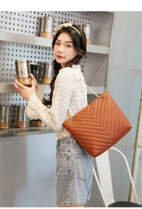 Détail d'un sac cabas matelassé marron caramel avec bandoulière en chaîne dorée