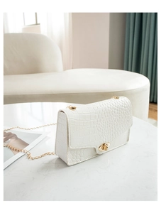 Detailed view of white crocodile pattern shoulder bag with gold chain and metal lock