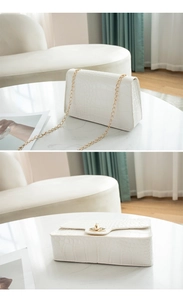 Detailed view of white crocodile pattern texture with golden chain and lock on small bag
