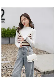 Detail of white crocodile pattern bag with gold chain strap on a casual outfit