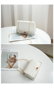 Detail view of white crocodile pattern shoulder bag with golden clasp and chain strap