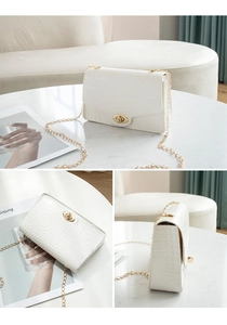 Detail view of white crocodile pattern flap bag with gold chain and oval twist lock