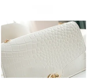 Detailed macro shot of white crocodile embossed texture and golden metal twist lock